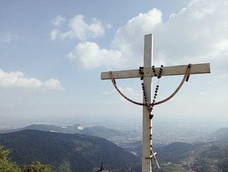 Cross on the top of the mountain with blue sky and white cloudsの写真素材