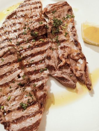 Grilled beef steak on white plate with lemon. Toned.の写真素材