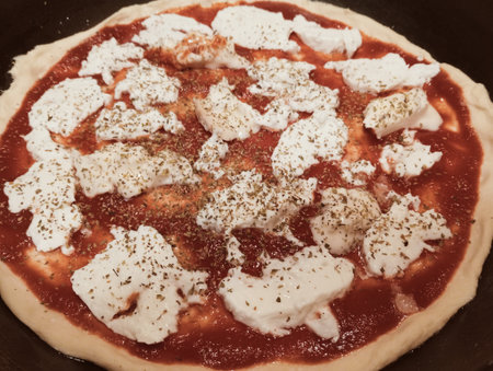 pizza with mozzarella and tomato sauce on a black plateの写真素材
