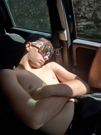 Young man sleeping on the back seat of a car in the sunの写真素材