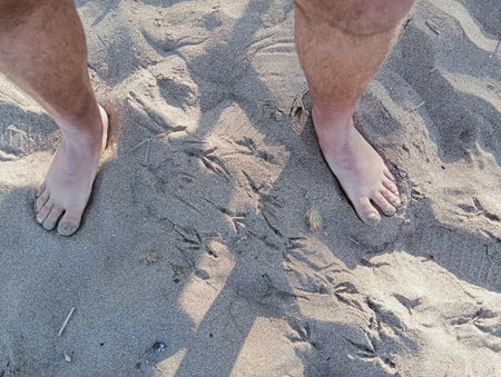 Man walking on the beach, close up of legs and feet.
