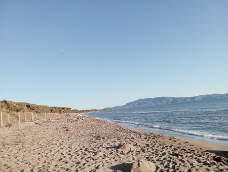 A woman sunbathing on a beach in the early morning sunの写真素材