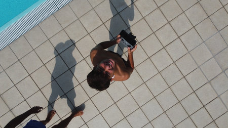 Top view of a man taking a photo of his girlfriend at the swimming poolの写真素材
