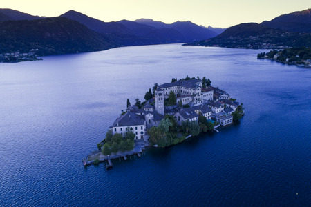 The very suggestive and romantic island of San Giulio in Orta lake, Piedmont, Italy. Aerial view at dusk.のeditorial素材