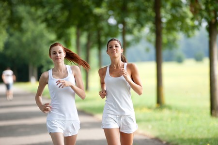 two young adult woman running to fitの写真素材