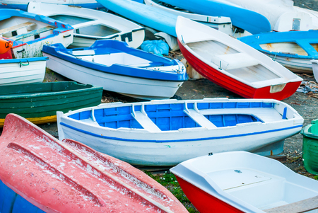 Fishing boats, left on the beach of the port, waiting to be painted and maintained, at the end of the summer seasonの写真素材