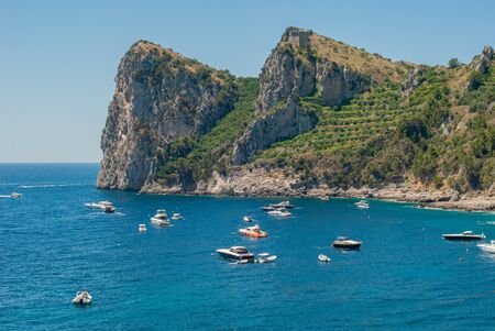 Three laces of the bay of Ieranto, with the Montalto Tower on the summit and boats at sea, taken from the beach of Nerano, near Sorrentoの写真素材