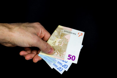 hand holding out some banknotes, on a dark background