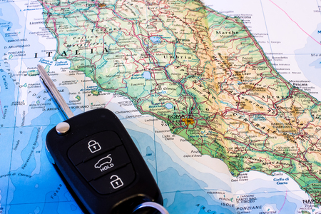 Planning road trip in central Italy represented by keys of car on road mapの写真素材