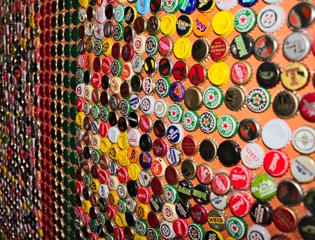 wall of a pub covered with multicolored caps of beerのeditorial素材