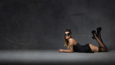 girl wiht mask lying down on the floor, dark backgroundの写真素材