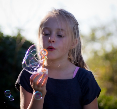 little girl playing with soap bubbles in natureの写真素材