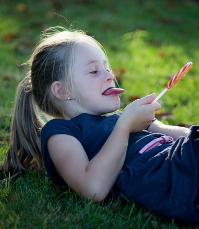 little girl with lollipop candy in natureの写真素材