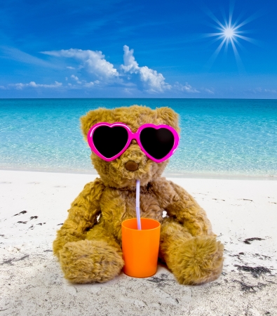 teddy bear sunbathing on a tropical beach and drinkingの写真素材