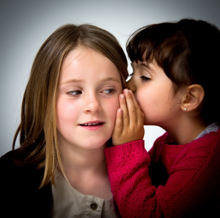 portrait of two little girls telling secretsの写真素材