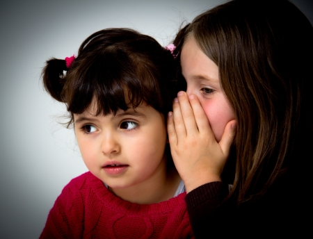 portrait of two little girls telling secretsの写真素材