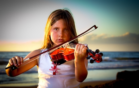 little girl playing violin on the beachの写真素材