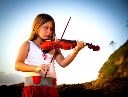 little girl playing violin on the beachの写真素材