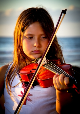 little girl playing violin on the beachの写真素材