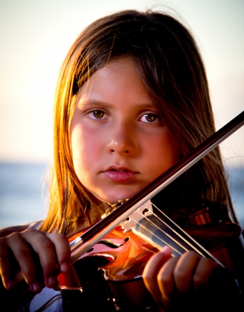 little girl playing violin on the beachの写真素材