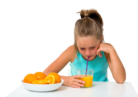 little girl with glass of orange juice isolated on whiteの写真素材