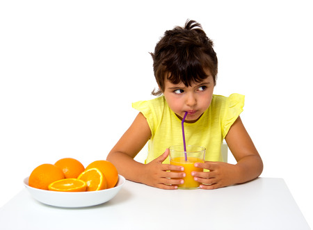 little girl with glass of orange juice isolated on whiteの写真素材