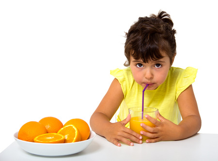 little girl with glass of orange juice isolated on whiteの写真素材