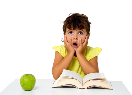 little girl reading a book with apple isolated on whiteの写真素材
