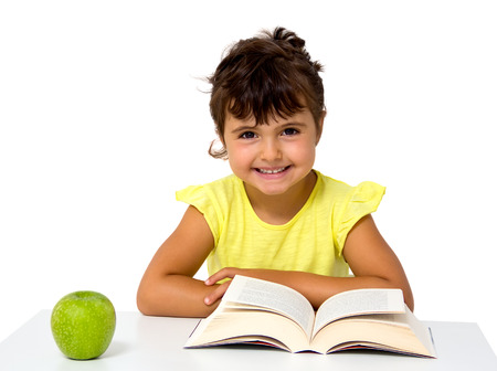 little girl reading a book with apple isolated on whiteの写真素材