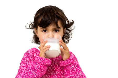 little girl with glass of milk isolated on whiteの写真素材