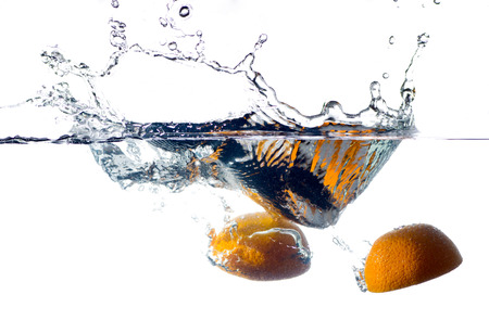 orange falling and splashing into clear water.の写真素材