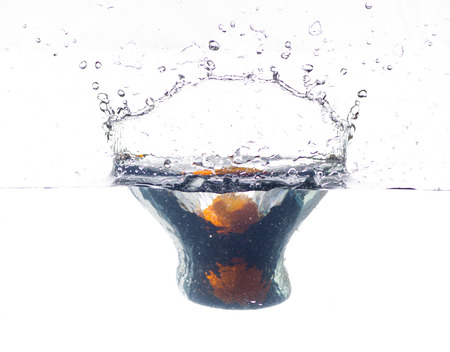 orange falling and splashing into clear water.の写真素材