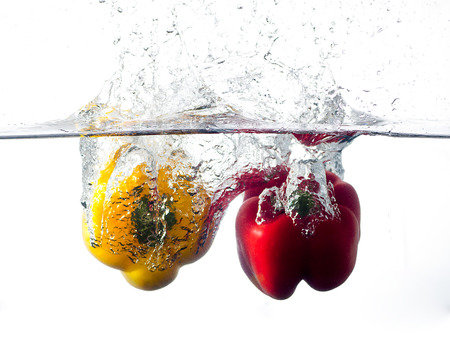 red and yellow pepper falling and splashing into clear water.の写真素材