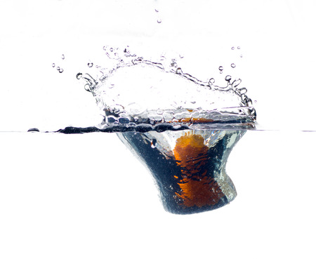 orange falling and splashing into clear water.の写真素材