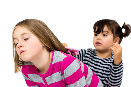 two little girls combing isolated on whiteの写真素材