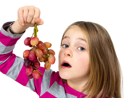 little girl with grapes isolated on whiteの写真素材