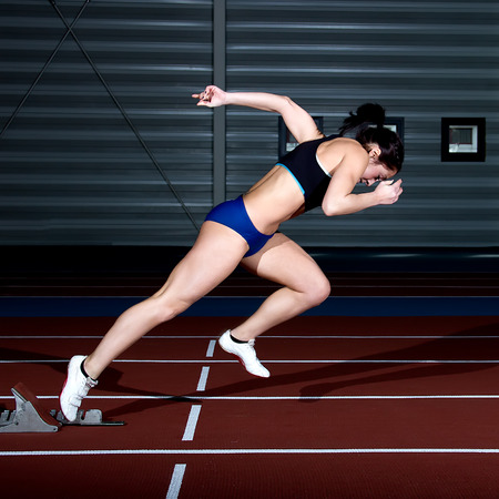 Woman sprinter leaps from starting block.の写真素材