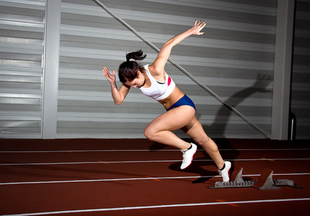 Woman sprinter leaps from starting block.の写真素材