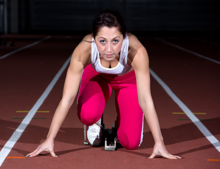 Woman sprinter leaps from starting block.の写真素材