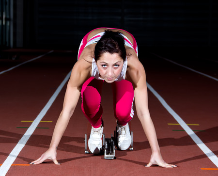 Woman sprinter leaps from starting block.の写真素材