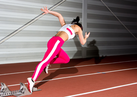 Woman sprinter leaps from starting block.の写真素材