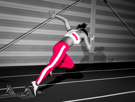 Woman sprinter leaps from starting block.の写真素材
