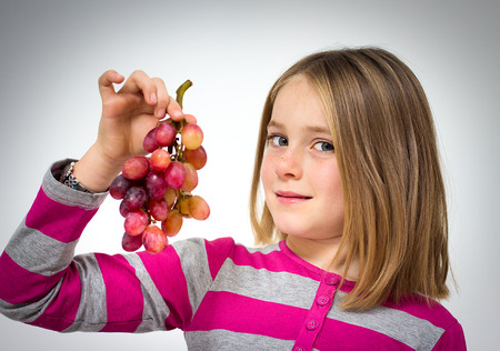 Portrait of a little girl with grapesの写真素材