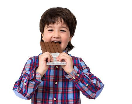 Little boy eating chocolate isolated on whiteの写真素材