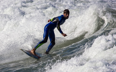 GIJON, SPAIN  Oct, 2014:  Athletes surfing on San Lorenzo beach located in GijÃ³n, in the north of...