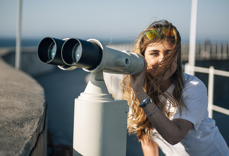 Portrait of a pretty teenage girl with a tourist telescopeの写真素材