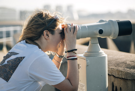 Portrait of a pretty teenage girl with a tourist telescope