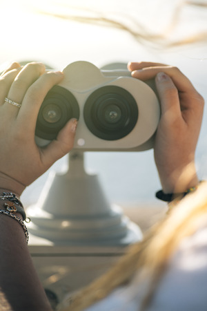 Portrait of a pretty teenage girl with a tourist telescopeの写真素材