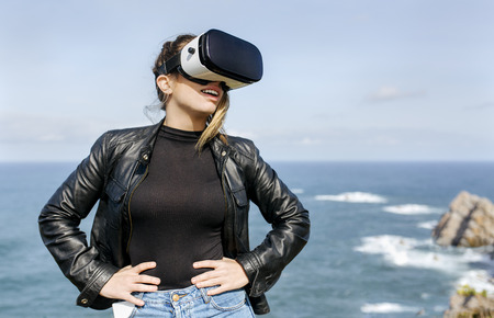 Woman using VR glasses on a rocky coastの写真素材