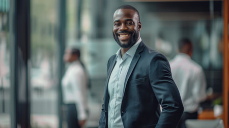 Portrait of a handsome smiling black businessman boss standing in his modern business company office.の素材